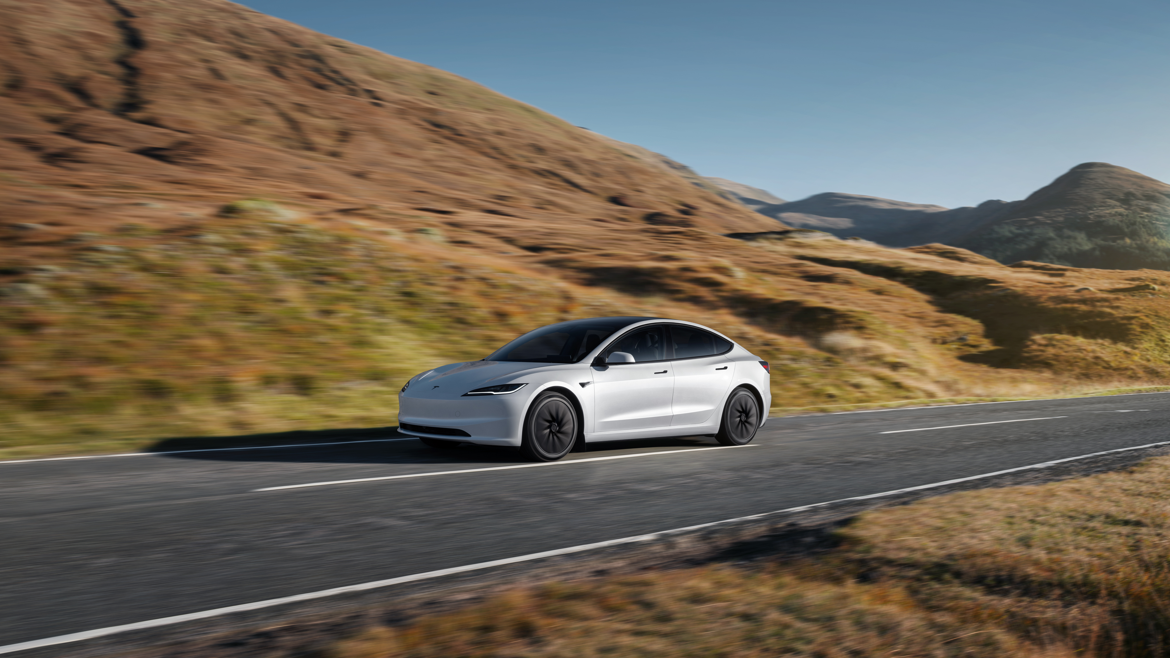 Tesla Model 3 driving on an autumn mountain road